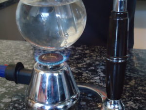 Coffee siphon with gas flame lit on cafe counter